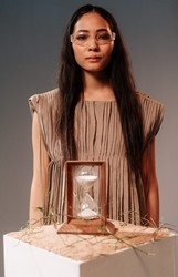 Brunette woman standing by hourglass by Ron Lach via Pexels.com.